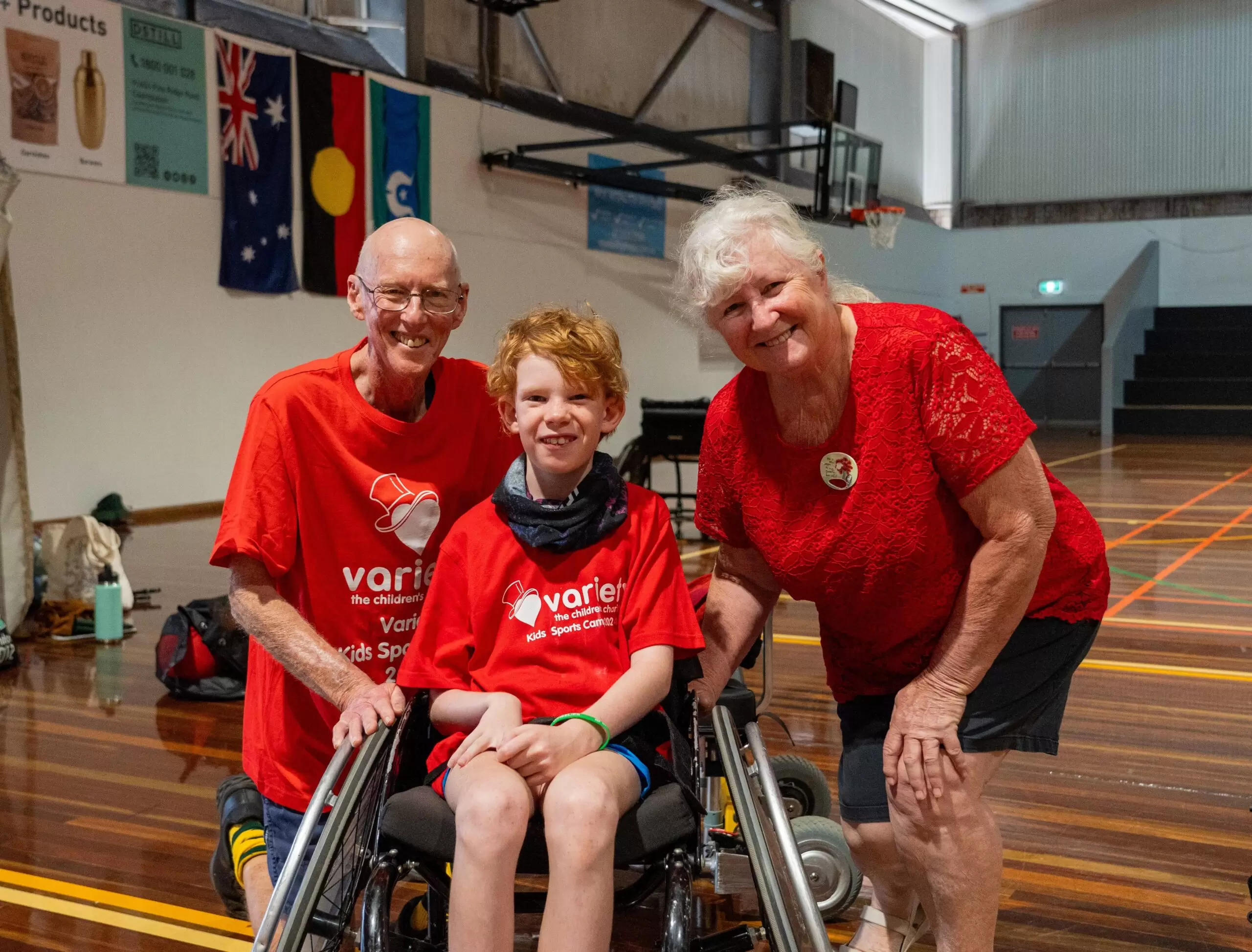 2 volunteers at variety event with young boy in sports wheel chair